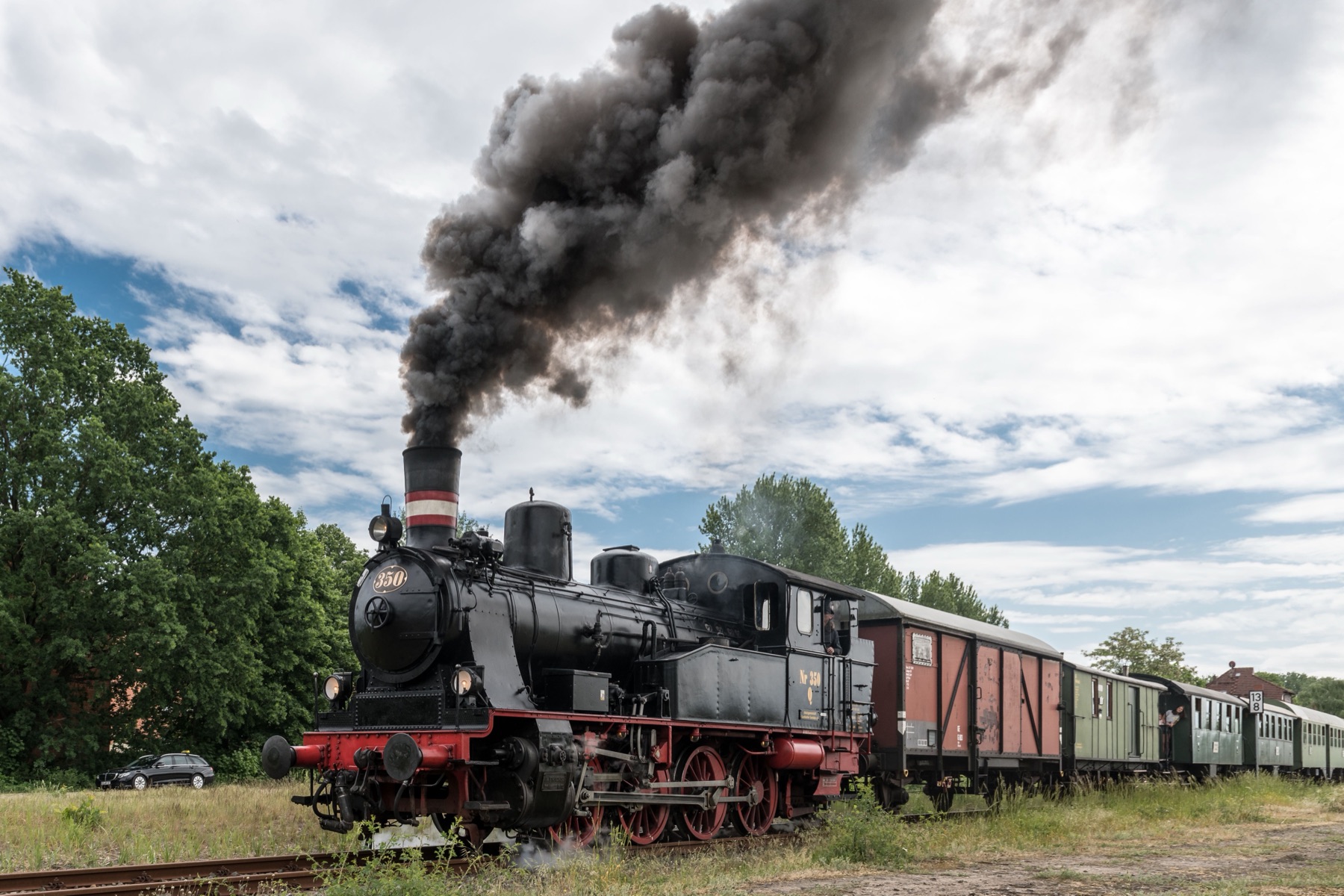 Old No. 350 departing under a full head of steam, black smoke billowing from her stack as she leads the excursion train past the meadow